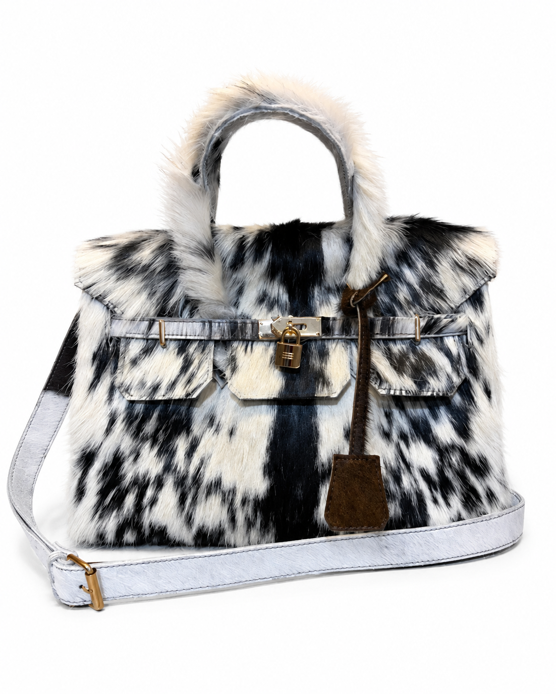 A structured handbag with a black and white cowhide pattern, featuring a faux fur trim on the handle, a light blue denim shoulder strap, and gold-tone hardware.