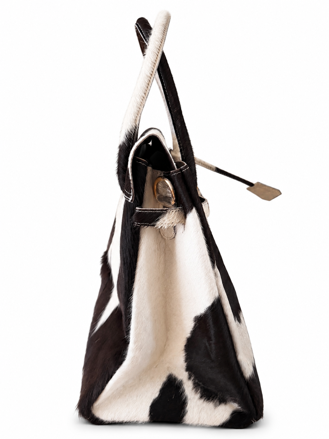 A cowhide shoulder bag with a black and white natural pattern, featuring a long handle and a small leather tag attached to a strap, shown against a plain white background.