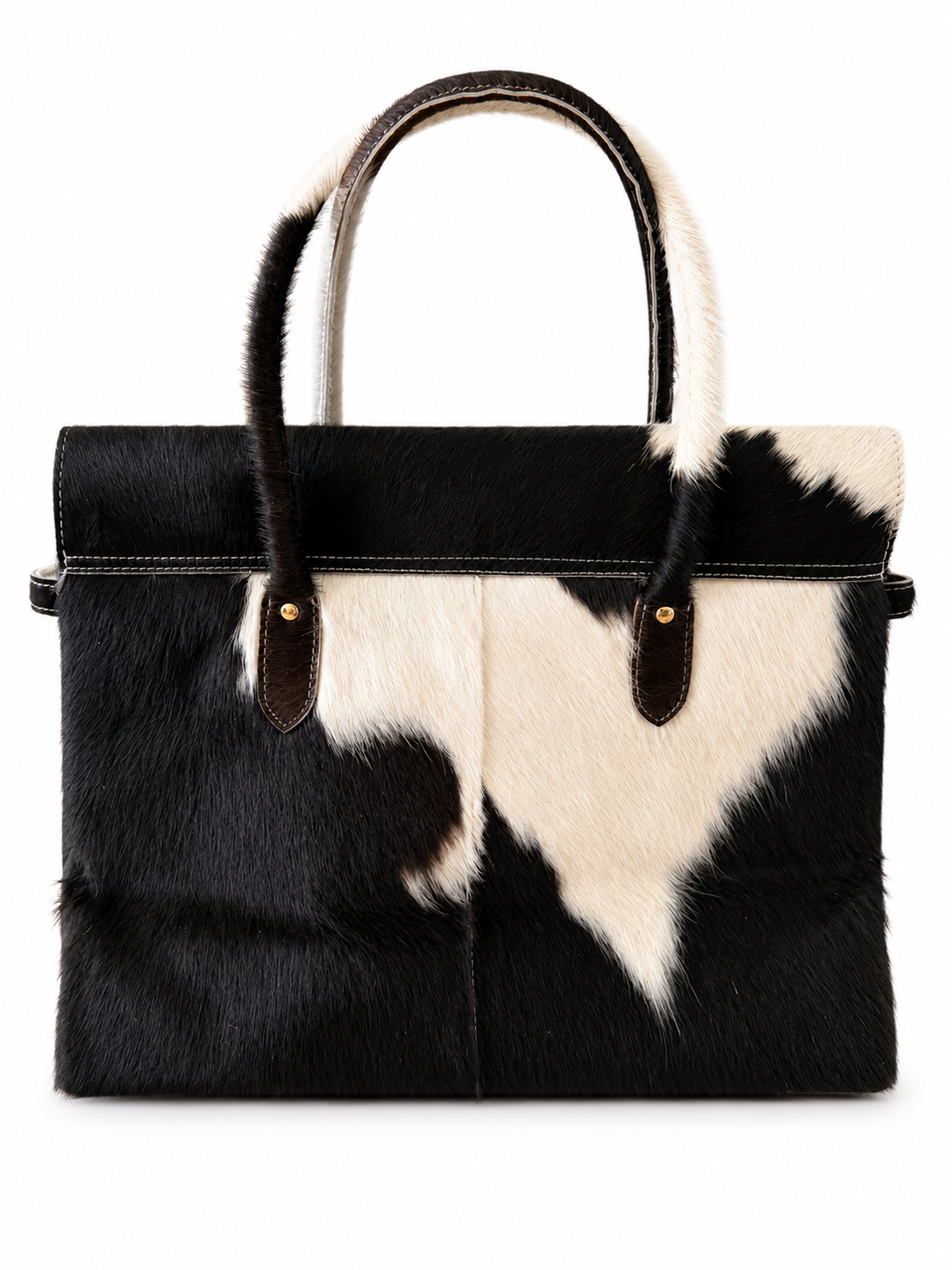 A structured handbag made of black and white cowhide with dark brown leather handles and hardware, shown against a plain white background.