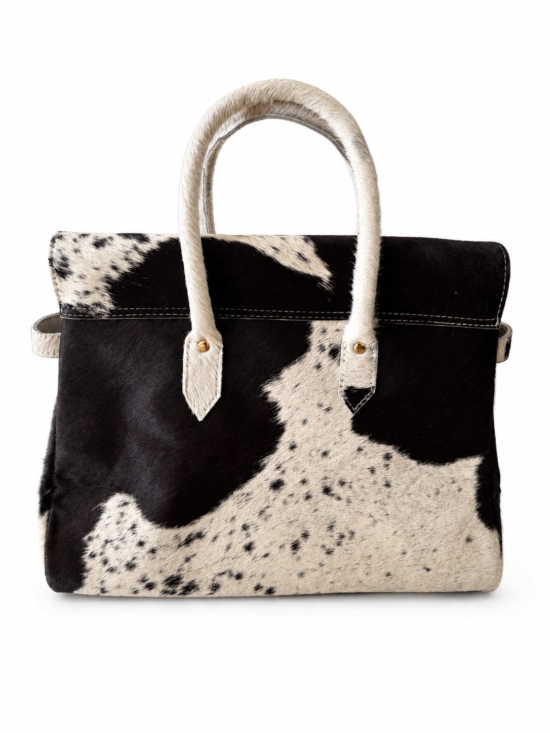 A structured handbag with a black and white cowhide pattern, featuring cream-colored handles and trim, photographed against a solid white background.