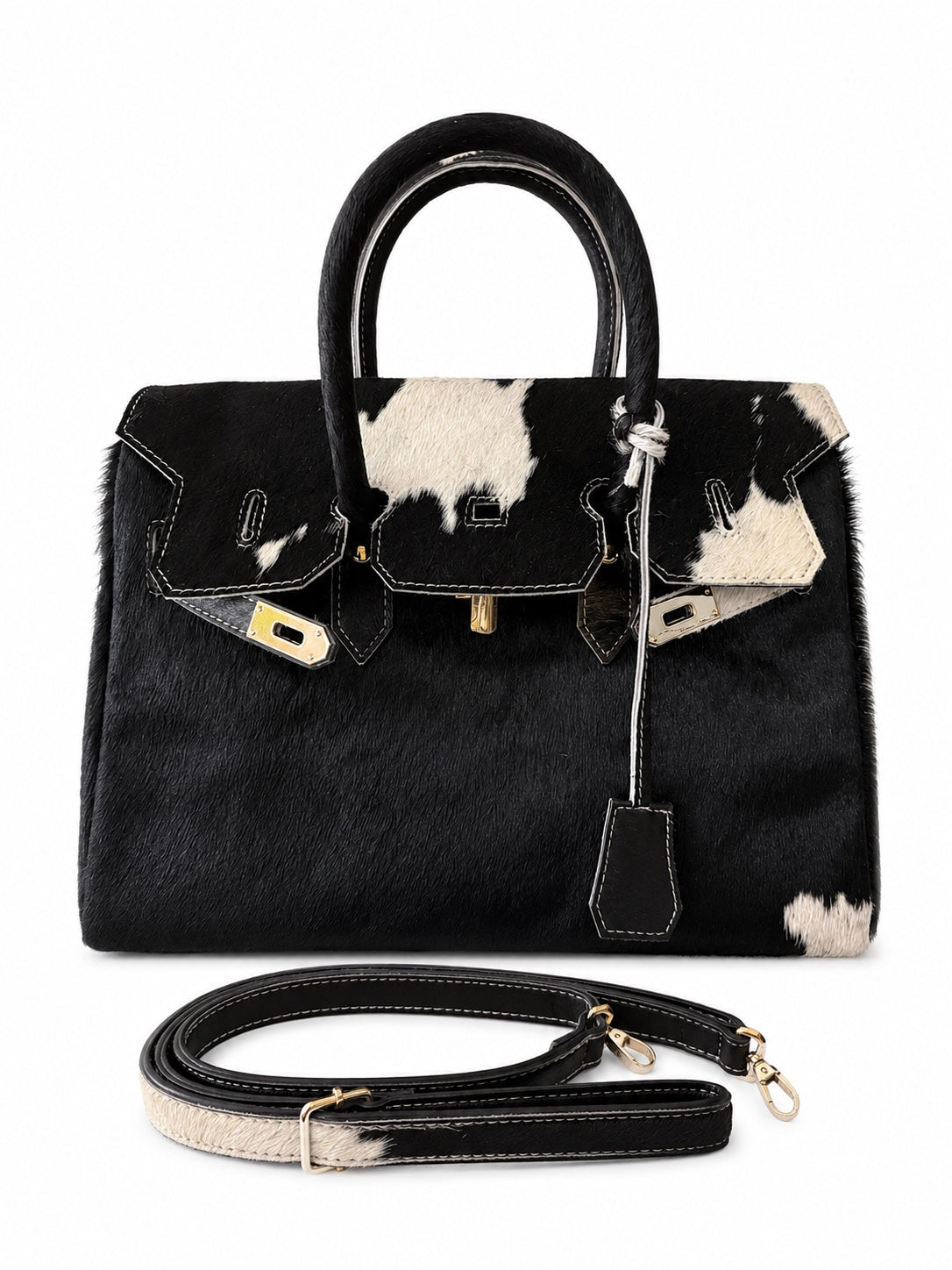 A structured black handbag with cowhide-patterned panels and trim, gold-tone hardware, dual top handles, and a detachable shoulder strap, photographed on a clean white background.
