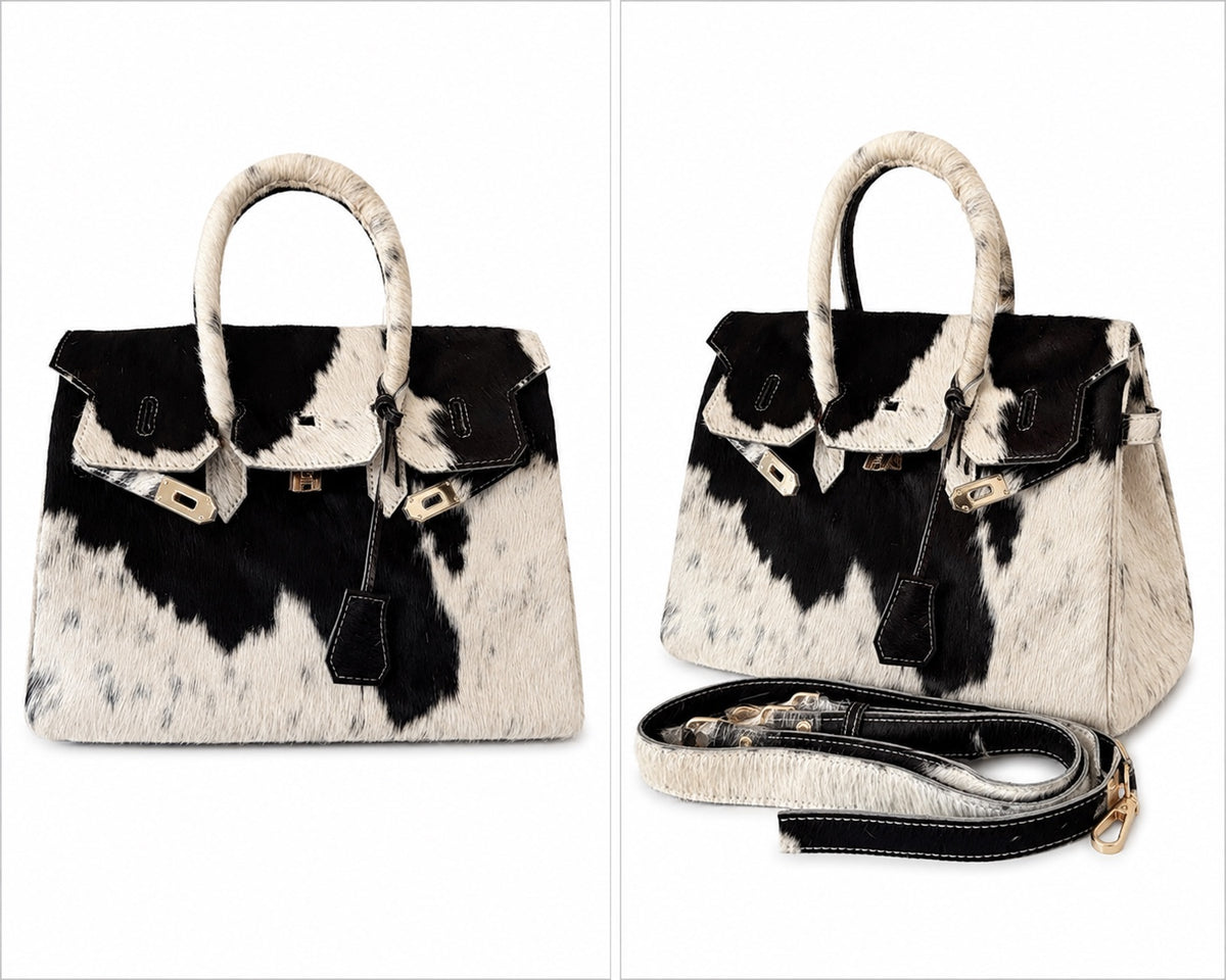 A structured handbag with a black and white cowhide pattern, featuring dual top handles, a front flap with leather trim, and a detachable shoulder strap, shown in two views on a white background.