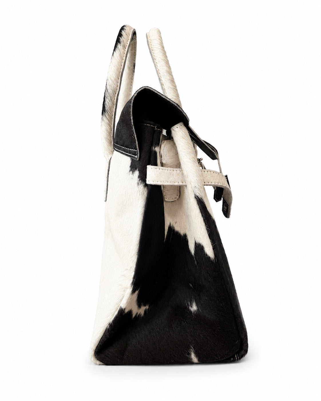 A structured handbag with a black and white cowhide pattern, featuring dual top handles and a black leather strap detail, shown against a plain white background.