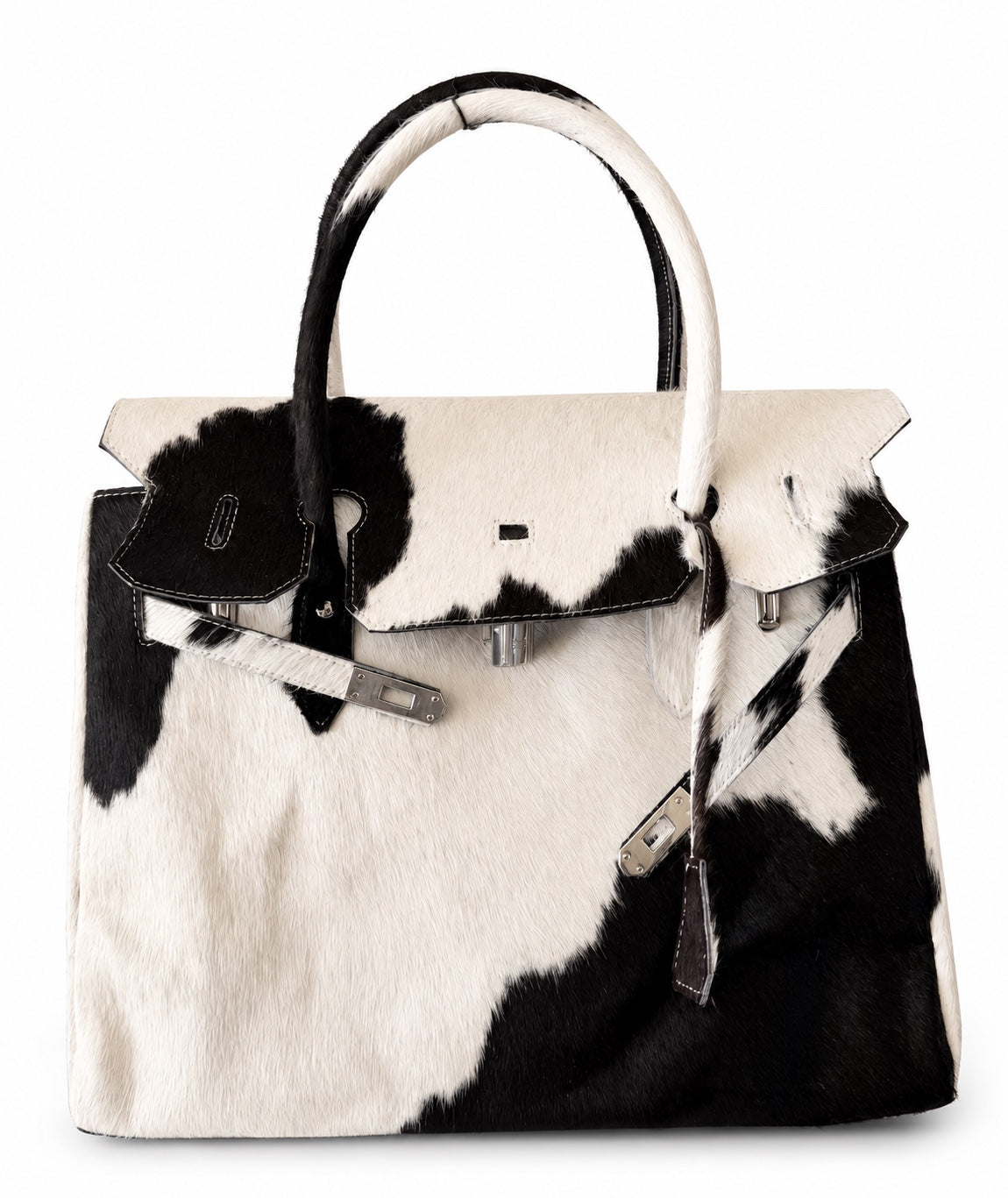 A structured handbag with a black and white cowhide pattern, featuring dual top handles, a front flap closure, and silver-tone hardware, shown against a plain white background.