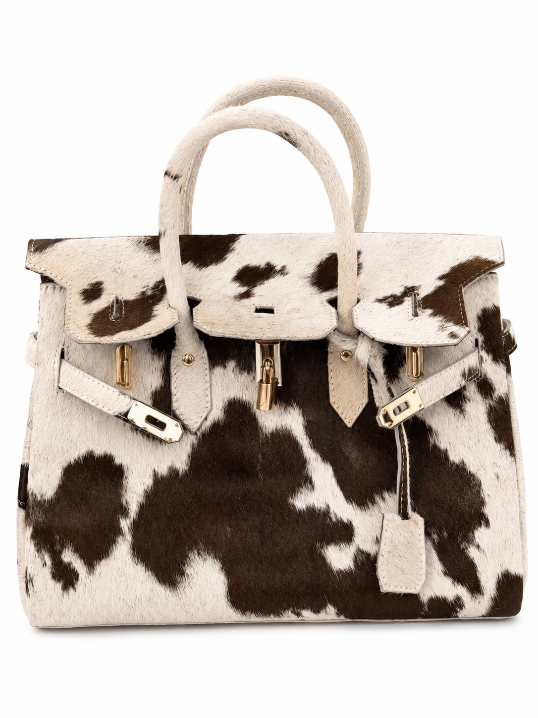 A structured handbag with a cowhide pattern in black and off-white, featuring dual top handles, a flap closure with gold-tone hardware, and a hanging leather tag.