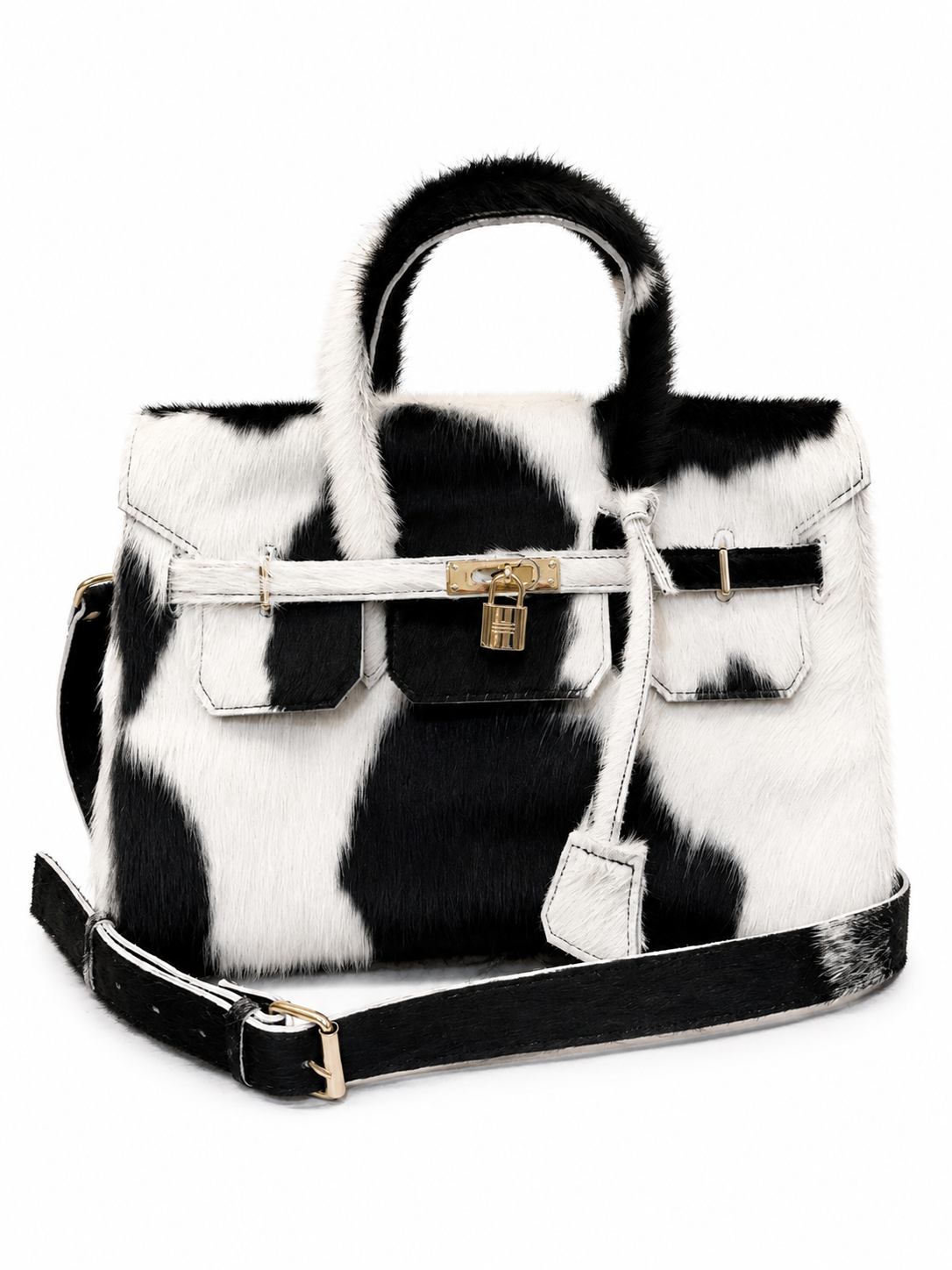 A structured handbag with a black and white cowhide pattern, featuring a black faux-fur top handle, a front flap with a white strap and gold padlock closure, and a matching black and white shoulder strap, set against a plain white background.