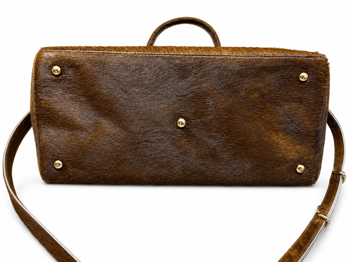A brown textured leather clutch or sleeve with a top handle and a detachable shoulder strap, shown against a plain white background.